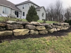 A stone wall in front of a house.