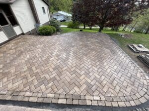 A brick paver patio is being installed in front of a house.